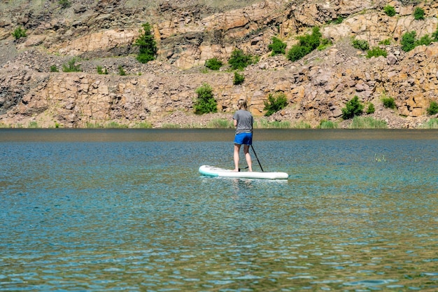 Donna a bordo di sup con pagaia nel lago