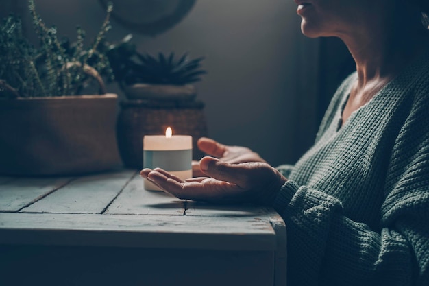 Donna a casa in attività di meditazione zen e lume di candela sullo sfondo Una donna con le mani alzate prega o medita da sola al buio al coperto Concetto di stile di vita mentale sano Natura