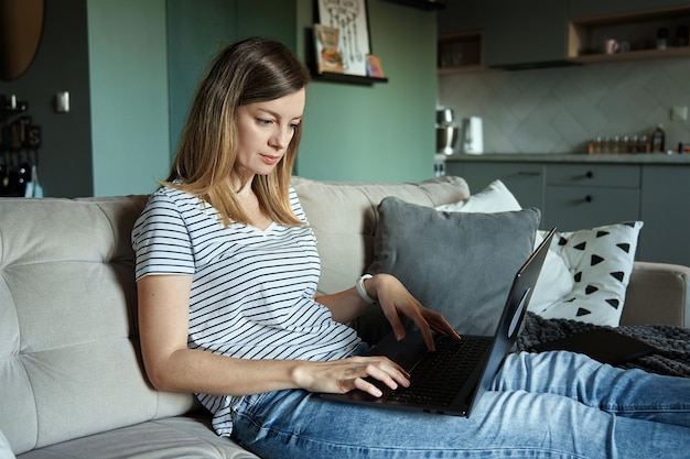 Donna a casa utilizzando il computer portatile Lavoro a distanza in ufficio a casa