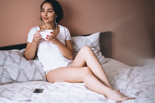 Donna a letto con caffè e telefono