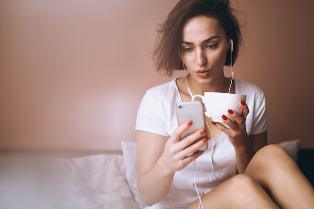 Donna a letto con caffè e telefono