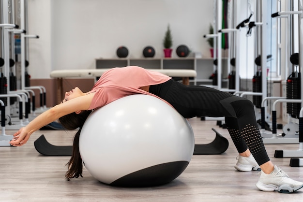 Donna a tutto campo che si esercita con la palla da ginnastica