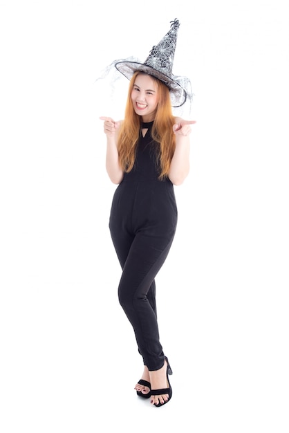 Donna abbastanza asiatica in cappello da portare della strega della tuta nera per il festival di Halloween isolato sopra fondo bianco.