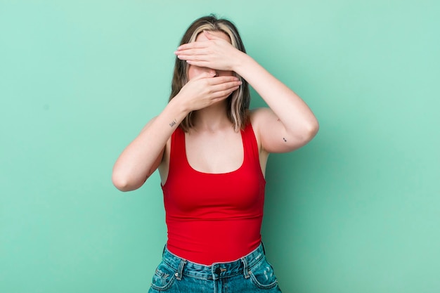 Donna abbastanza caucasica che copre il viso con entrambe le mani dicendo di no alla fotocamera rifiutando le foto o vietando le foto