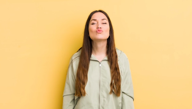 Donna abbastanza caucasica che preme le labbra insieme a un'espressione adorabile felice divertente carina che invia un bacio