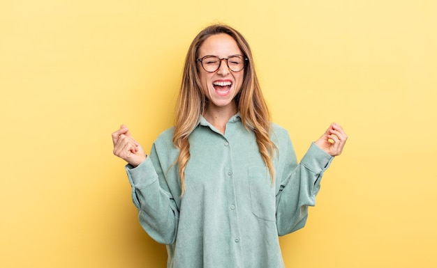 Donna abbastanza caucasica che sembra estremamente felice e sorpresa, celebrando il successo, gridando e saltando