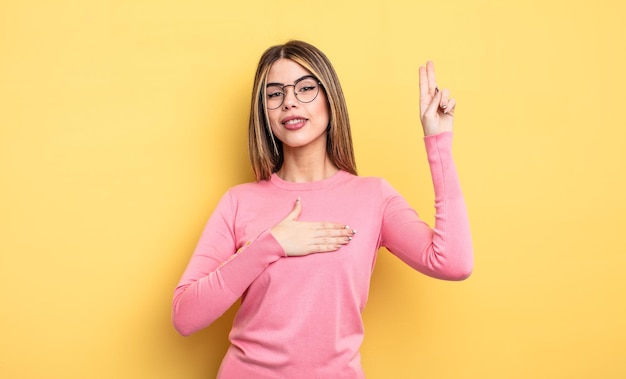 Donna abbastanza caucasica che sembra felice, sicura di sé e degna di fiducia, sorridente e mostra il segno della vittoria con un atteggiamento positivo