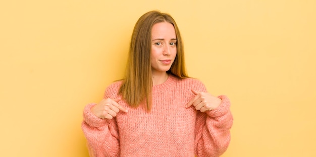 Donna abbastanza caucasica che sembra orgogliosa positiva e casual che punta al petto con entrambe le mani