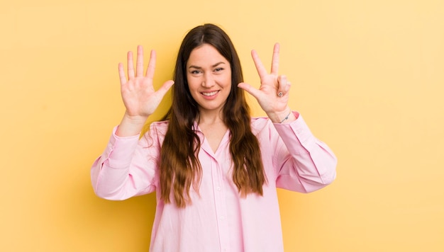 Donna abbastanza caucasica che sorride e che sembra amichevole che mostra il numero otto o ottavo con il conto alla rovescia in avanti della mano