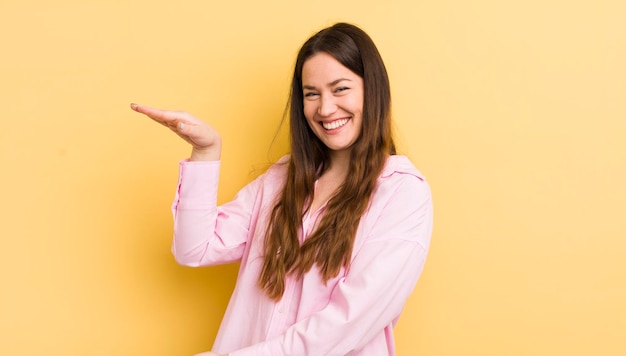 Donna abbastanza caucasica sorridente che si sente felice positiva e soddisfatta che tiene o mostra un oggetto o un concetto sullo spazio della copia