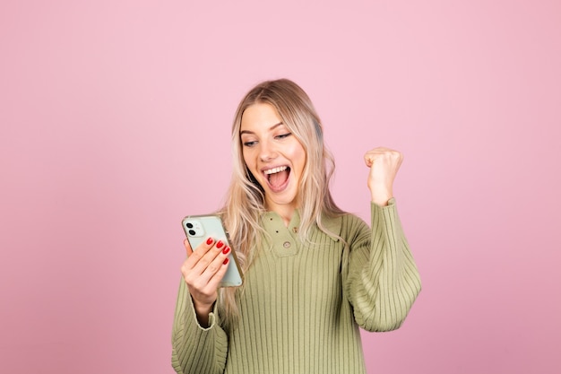 Donna abbastanza europea in maglione lavorato a maglia casual sulla parete rosa