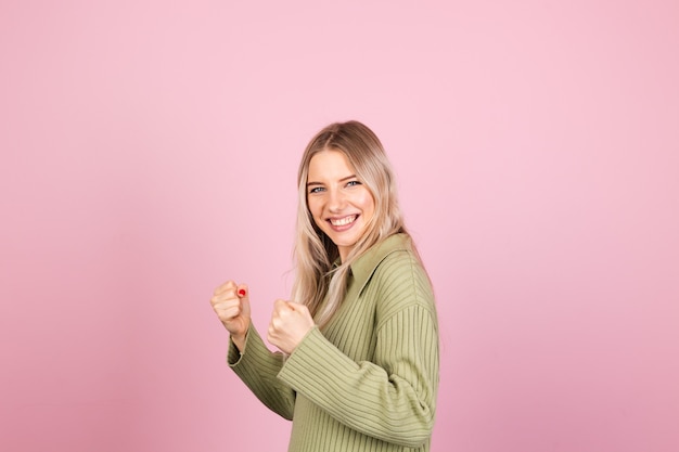 Donna abbastanza europea in maglione lavorato a maglia casual sulla parete rosa