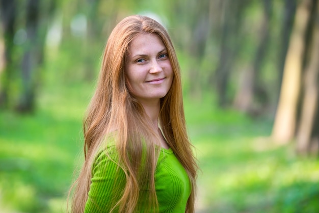 Donna abbastanza felice con i capelli lunghi rossi nel parco verde primaverile