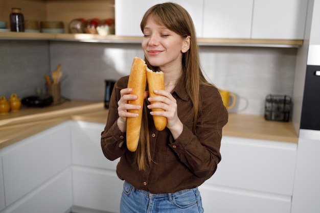 Donna abbastanza giovane che annusa una baguette francese fresca