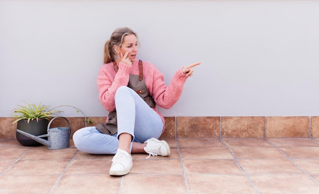 Donna abbastanza giovane che guarda e si siede sul pavimento all'aperto