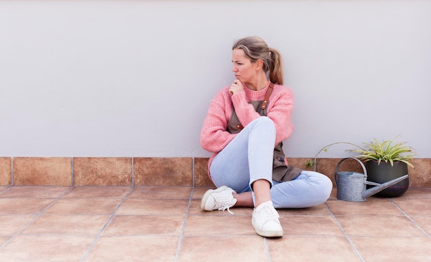 Donna abbastanza giovane che guarda e si siede sul pavimento all'aperto