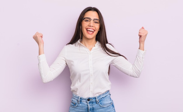 Donna abbastanza giovane che sembra estremamente felice e sorpresa che celebra il successo gridando e saltando