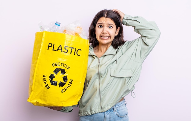 Donna abbastanza giovane che si sente stressata, ansiosa o spaventata, con le mani sulla testa. concetto di riciclaggio della plastica