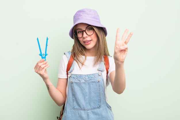 Donna abbastanza giovane che sorride e che sembra amichevole, mostrando il numero tre. concetto di studente