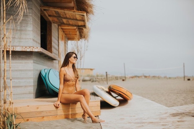 Donna abbastanza giovane in bikini che si siede sulla spiaggia al giorno d'estate