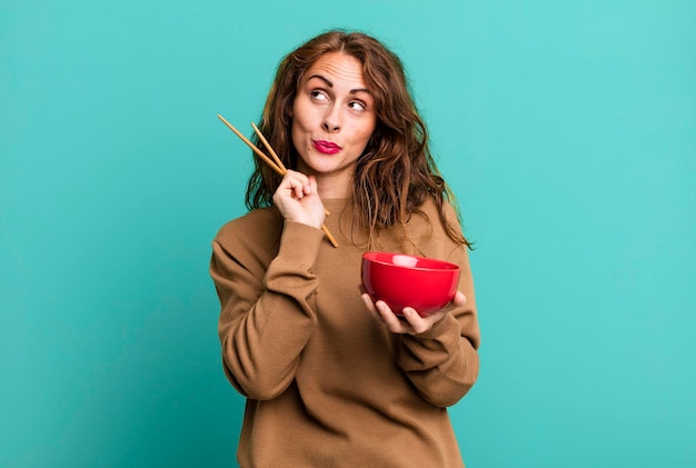 Donna abbastanza giovane ispanica che mangia una ciotola di tagliatelle giapponesi