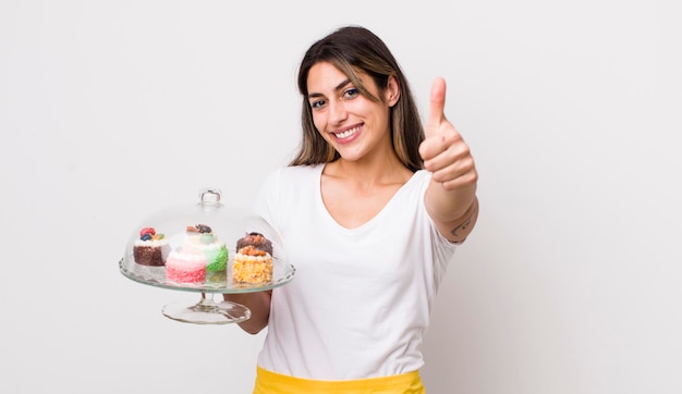 Donna abbastanza ispanica che si sente orgogliosa di sorridere positivamente con i pollici in su concetto di torte fatte in casa