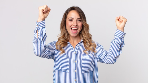 Donna abbastanza magra che grida trionfalmente, sembra un vincitore eccitato, felice e sorpreso, festeggiando