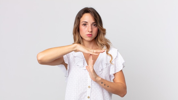 Donna abbastanza magra che sembra seria, severa, arrabbiata e dispiaciuta, facendo il segno del time out