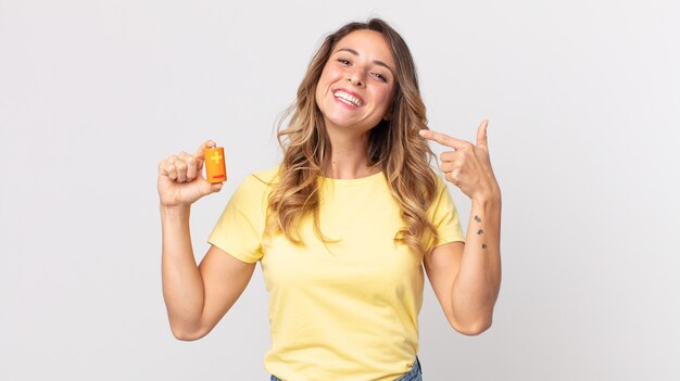 Donna abbastanza magra che sorride con sicurezza indicando il proprio ampio sorriso e tenendo le batterie