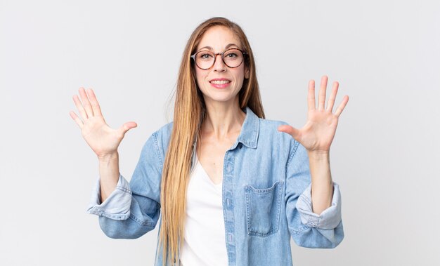 Donna abbastanza magra che sorride e sembra amichevole, mostrando il numero dieci o decimo con la mano in avanti, conto alla rovescia