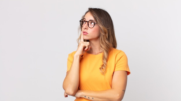 Donna abbastanza magra con uno sguardo concentrato, chiedendosi con un'espressione dubbiosa, guardando in alto e di lato