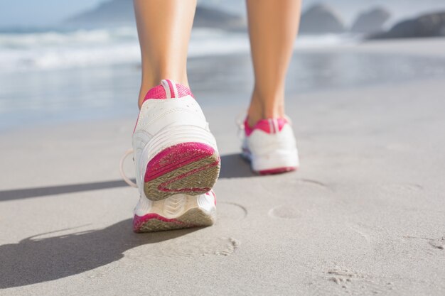 Donna adatta che cammina sulla spiaggia