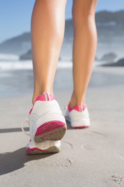 Donna adatta che cammina sulla spiaggia