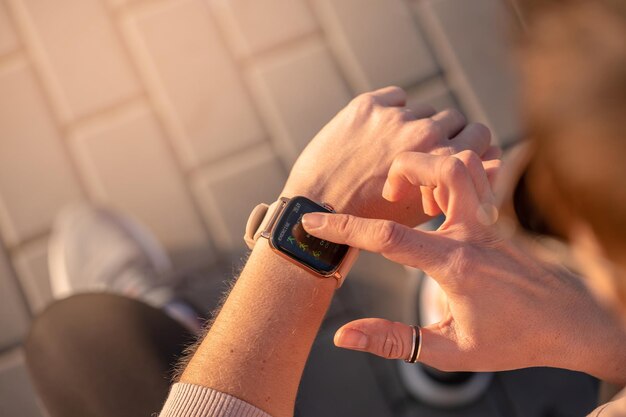 Donna adatta che controlla la tecnologia indossabile dell'orologio intelligente, smartwatch sportivo sulla corsa fitness cammina fuori. Vista dall'alto con scarpe da corsa in strada.