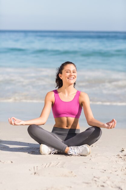 Donna adatta che fa yoga al lato del mare