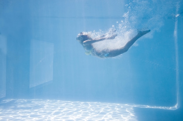 Donna adatta che nuota sotto l&#39;acqua in piscina