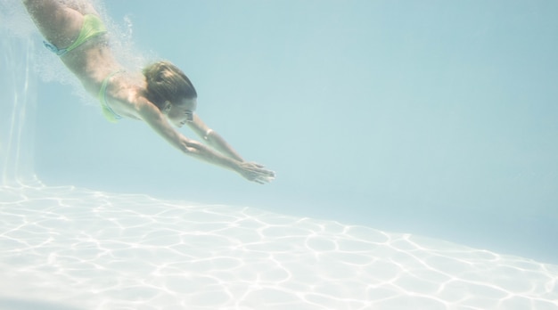 Donna adatta che nuota sotto l&#39;acqua in piscina