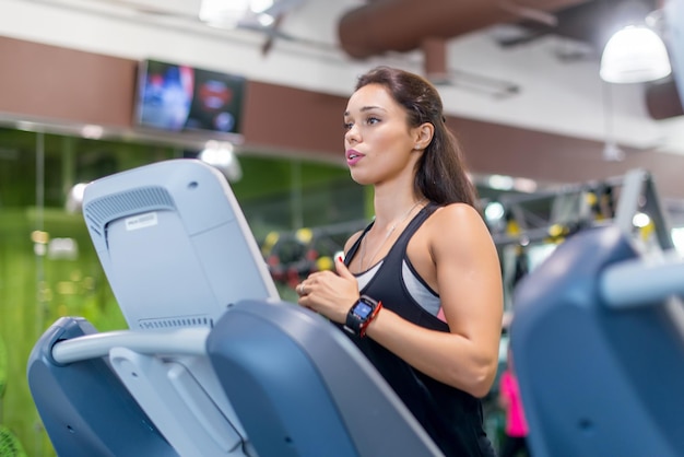 Donna adatta che si esercita sul tapis roulant in palestra