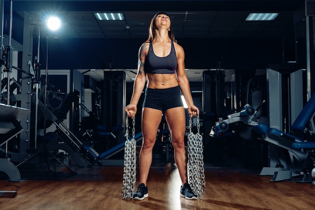 Donna adatta nei collegamenti a catena di una tenuta della palestra