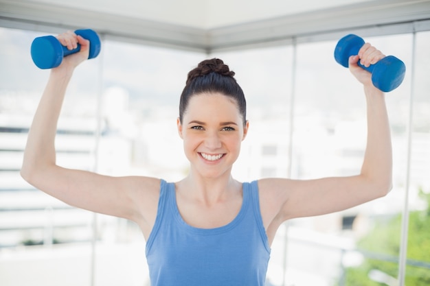 Donna adatta sorridente che si esercita con i dumbbells