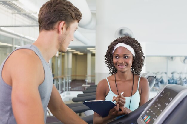 Donna adatta sul tapis roulant che parla con personal trainer