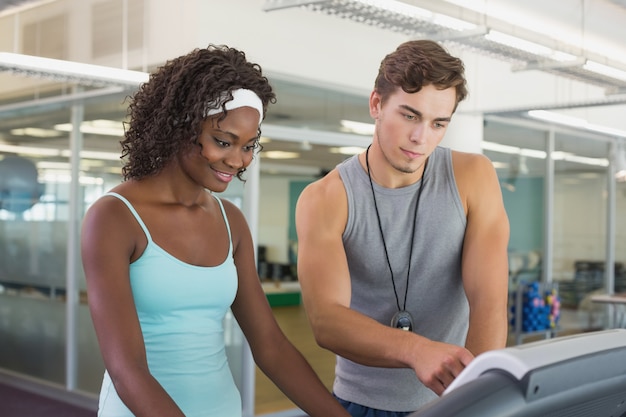 Donna adatta sul tapis roulant che parla con personal trainer