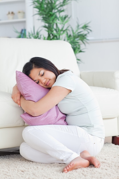 Donna addormentata che tiene un cuscino mentre si siede sul pavimento