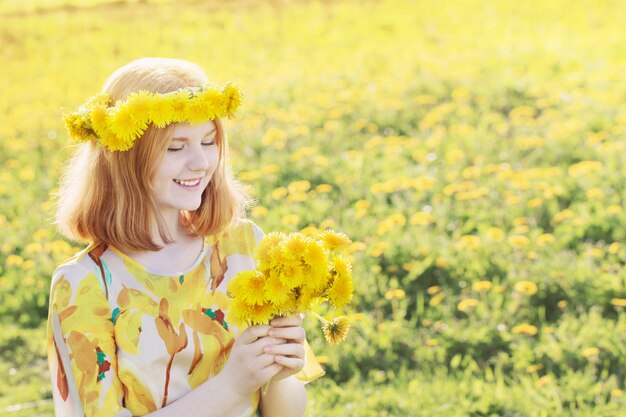 Donna adolescente bella con denti di leone gialli