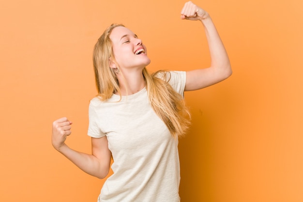 Donna adolescente carina e naturale che alza il pugno dopo una vittoria, concetto di vincitore.