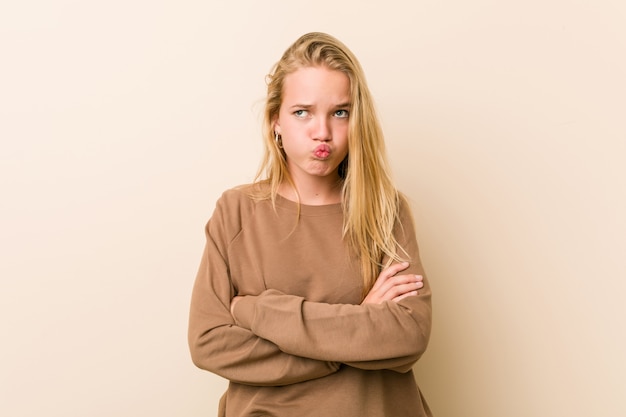 Donna adolescente carina e naturale soffia sulle guance, ha un'espressione stanca. Concetto di espressione facciale.