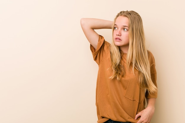 Donna adolescente carina e naturale toccando la parte posteriore della testa, pensando e fare una scelta.