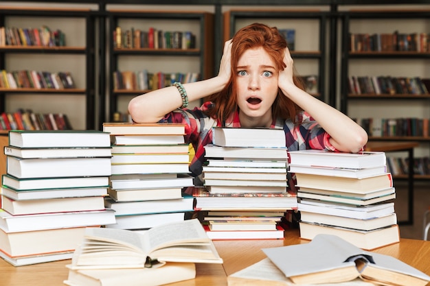 Donna adolescente disperata seduta in biblioteca