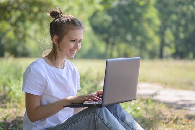 Donna adorabile con il computer portatile all'aperto