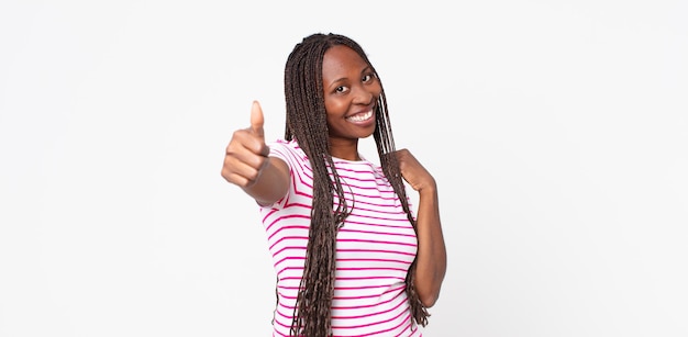 Donna adulta afro nera che si sente orgogliosa, spensierata, sicura di sé e felice, sorridendo positivamente con i pollici in su